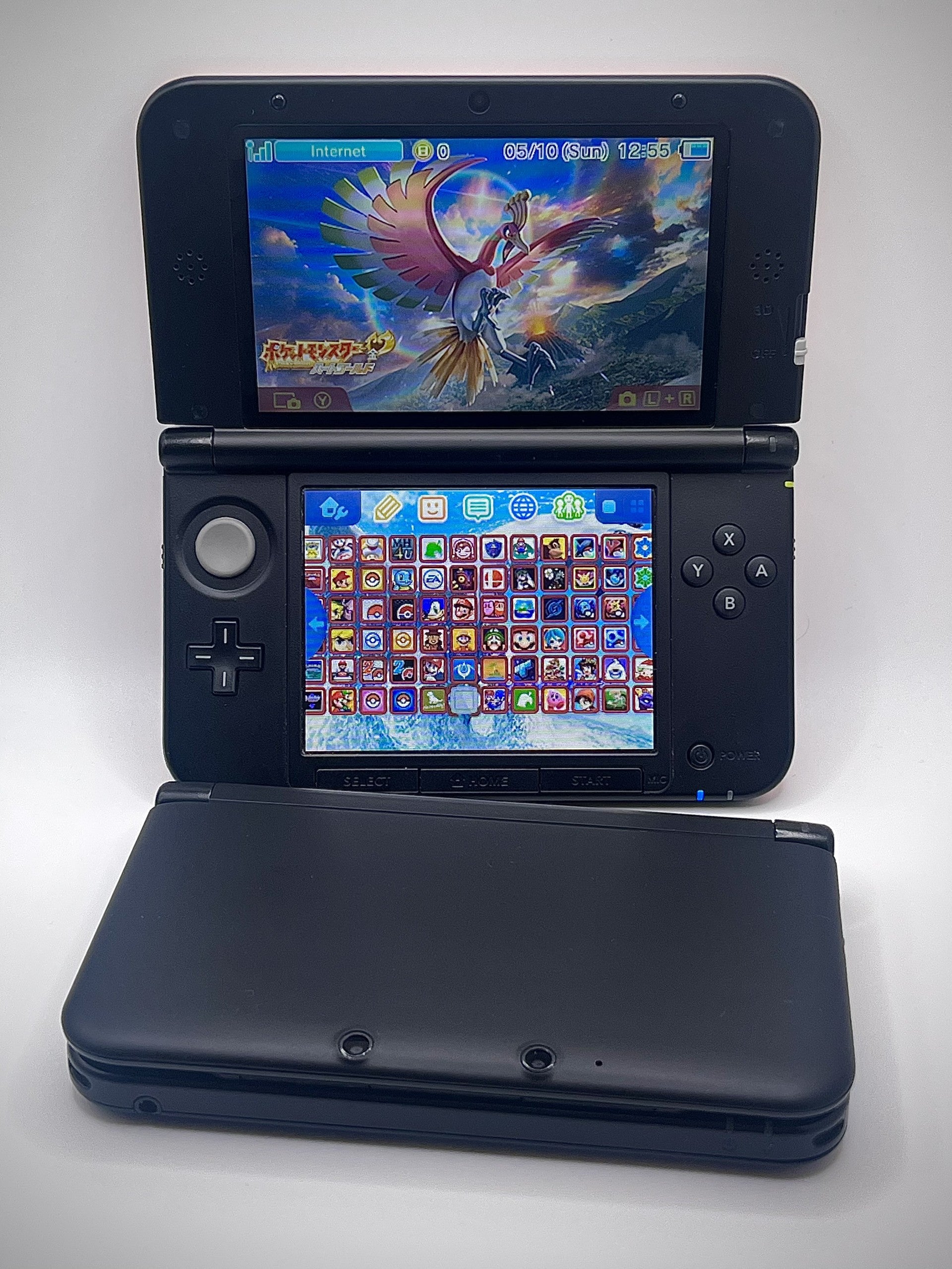 Black Nintendo 3DS gaming console with games displayed on the screen against a white background
